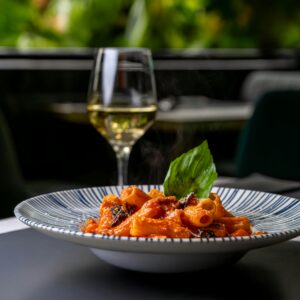 Appetizing rigatoni pasta with tomato sauce and white wine in an elegant setting.