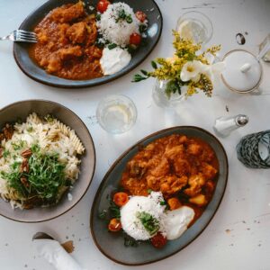 An inviting arrangement of Italian pasta and Indian curry dishes on a light surface.